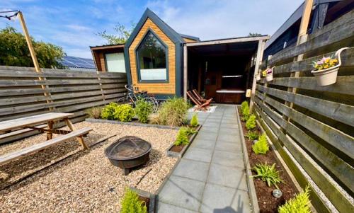 un piccolo giardino con panchina e casa di Tiny house with sauna & jacuzzi near Amsterdam a Vijfhuizen