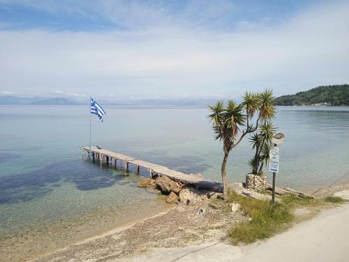 Sailors Luxury Cottage في Agia Pelagia Chlomou: رصيف مع العلم والنخيل على الماء