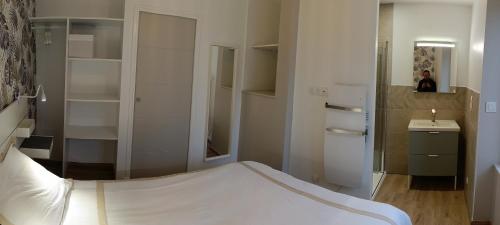 ein Schlafzimmer mit einem weißen Bett und einem Waschbecken in der Unterkunft Aux nids douillets Mayetois "les hirondelles" in Mayet-de-Montagne