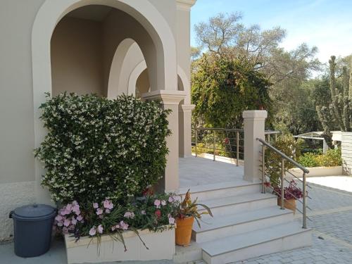 Sailors Luxury Cottage في Agia Pelagia Chlomou: مدخل لبيت فيه درج وزهور