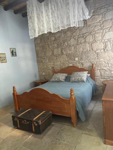 a bedroom with a wooden bed and a stone wall at Vasilion Agrotourism in Polis Chrysochous