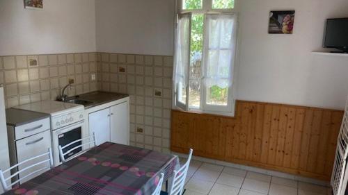 une cuisine avec une table et une cuisinière ainsi qu'une fenêtre dans l'établissement La petite plage de la Pège, à Saint-Hilaire-de-Riez