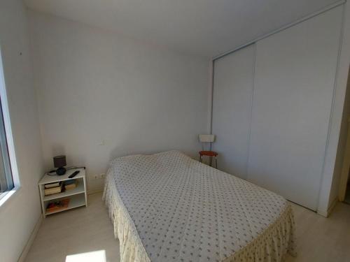 a white bedroom with a bed and a night stand at La baie de Sion in Saint-Hilaire-de-Riez