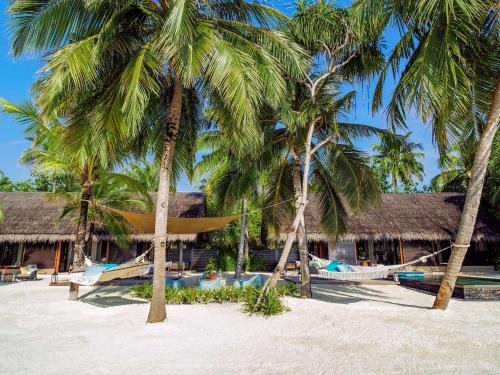 a resort with palm trees and a hammock on the beach at One&Only Reethi Rah in Reethi Rah
