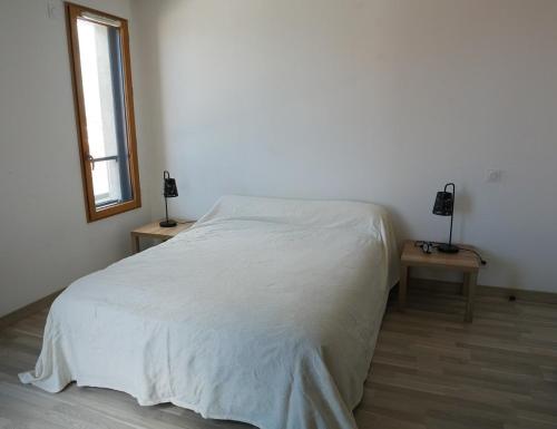 a white bed in a room with two lamps on tables at La perle océane de St Gilles in Saint-Gilles-Croix-de-Vie