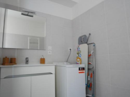 a kitchen with white cabinets and a refrigerator at La perle océane de St Gilles in Saint-Gilles-Croix-de-Vie