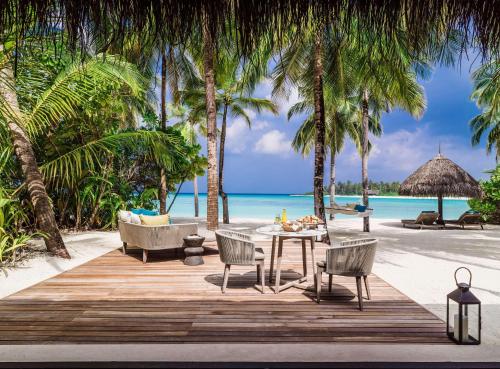 a table and chairs on a beach with the ocean at One&Only Reethi Rah in Reethi Rah