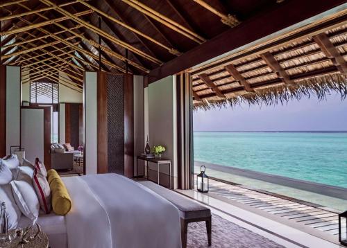 a bedroom with a bed and a view of the ocean at One&Only Reethi Rah in Reethi Rah