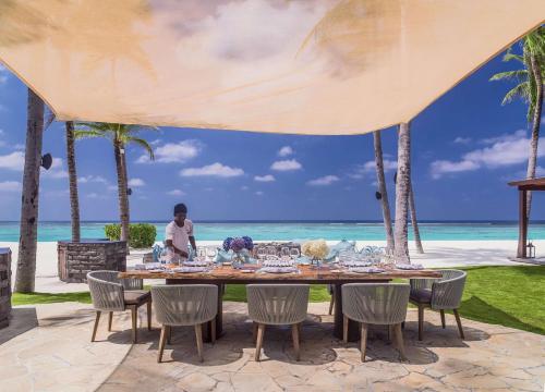 a table at a resort with the ocean in the background at One&Only Reethi Rah in Reethi Rah
