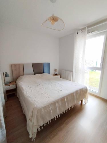 une chambre blanche avec un grand lit et une fenêtre dans l'établissement Le Cocon de la baie de Sion, à Saint-Hilaire-de-Riez