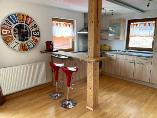 une cuisine avec un comptoir et deux tabourets rouges dans l'établissement Meridiana 2, à Tuntenhausen