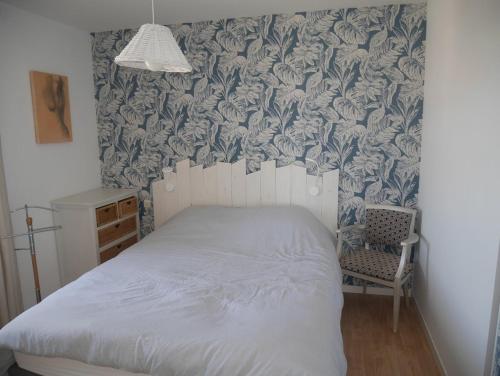 - une chambre avec un lit et une chaise avec du papier peint dans l'établissement Le bel'vue de St Hilaire, à Saint-Hilaire-de-Riez
