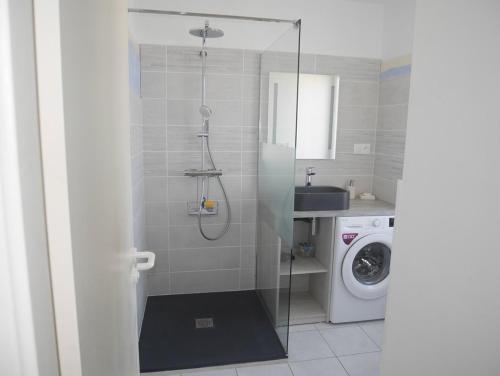 une salle de bain avec douche et machine à laver dans l'établissement Le bel'vue de St Hilaire, à Saint-Hilaire-de-Riez