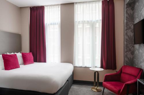 Habitación de hotel con cama y silla roja en Krisotel, en Ámsterdam