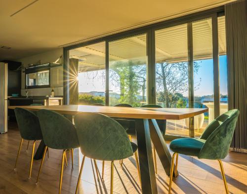 a dining room with a table and green chairs at Apartamento Con Jardín Rodeado de Viñedos in Ribadumia