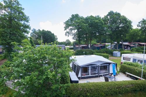 a tent in a park with trees and houses at Randbøldal Camping & Cabins in Randbøl