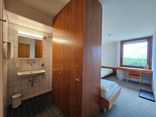 uma casa de banho com um lavatório, uma cama e um espelho. em Hotel Simplicity by Bad Schönbrunn em Menzingen