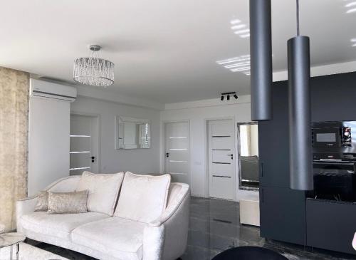 ein Wohnzimmer mit einem weißen Sofa und einer Küche in der Unterkunft Oxygen Home in Nyíregyháza