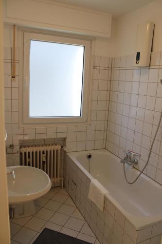 ein Bad mit einer Badewanne, einem Waschbecken und einem Fenster in der Unterkunft Zweites Zuhause in Recklinghausen