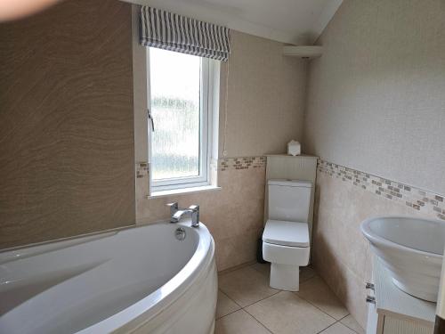 uma casa de banho com uma banheira, um WC e um lavatório. em Wold View Country Park & Fisheries Lodges 1 and 9 em Market Rasen