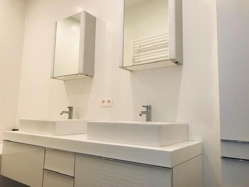 - une salle de bains blanche avec deux lavabos et un miroir dans l'établissement Prachtig gerenoveerd appartement, à Ostende