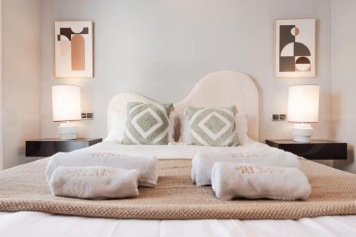 een wit bed met 2 kussens en 2 lampen bij Apartment with terrace steps from beach REMS in Fuengirola