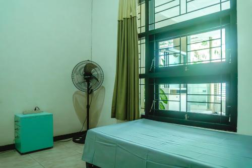 Sumanas Homestay Ijen في بانيووانجى: غرفة نوم بها سرير ونافذة بها مروحة