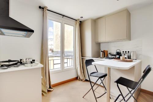 une cuisine avec une table et des chaises et une fenêtre dans l'établissement Appartement 2 personnes - Tour Eiffel, à Paris
