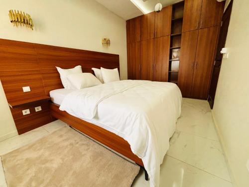 Schlafzimmer mit einem großen Bett mit einem Kopfteil aus Holz in der Unterkunft Medina Baye Résidence Boutique Hôtel in Kaolack