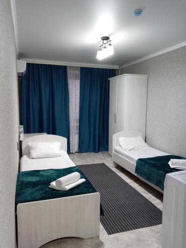2 łóżka w pokoju z niebieskimi zasłonami w obiekcie Silk Way w mieście Semej