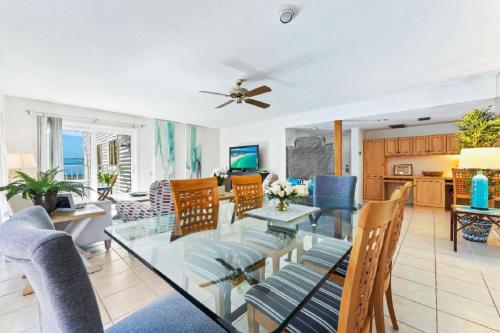 a dining room and living room with a glass table and chairs at Coastal Surfside By Beachside Management in Siesta Key