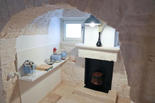 - une cheminée en pierre dans une chambre avec fenêtre dans l'établissement TRULLI OCCHI DI PIETRA HISTORICAL EXPERIENCE, à Alberobello