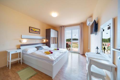 a bedroom with a large white bed and a window at Guesthouse Mira in Rab