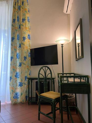 a room with a tv and a chair and a table at Hotel Baia Delle Sirene in Taormina