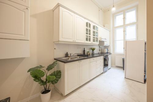 une cuisine avec des armoires blanches et une plante en pot dans l'établissement Cozy Boulevard Apartment in the Heart of Budapest, à Budapest