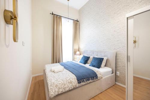 a white bedroom with a bed with blue pillows at Cozy Boulevard Apartment in the Heart of Budapest in Budapest