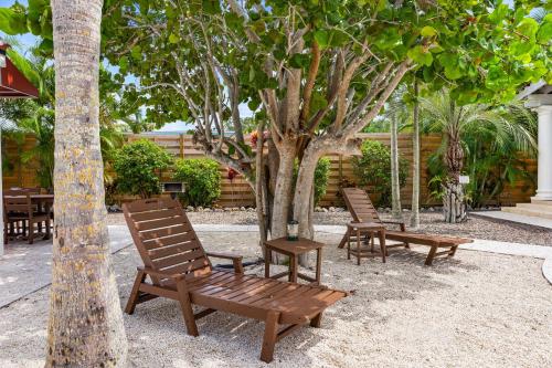 two wooden chairs sitting next to a tree at Crescent Beach Villas By Beachside Management in Siesta Key