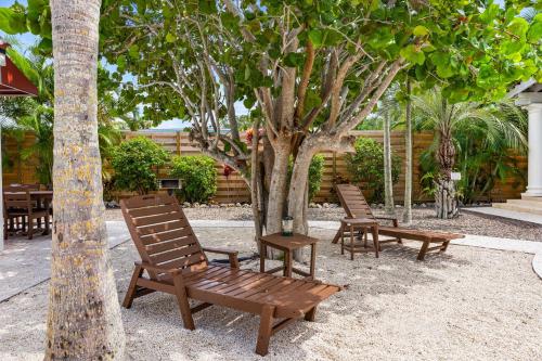 two wooden chairs sitting next to a tree at Crescent Beach Villas in Siesta Key
