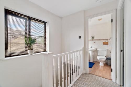 a white bathroom with a toilet and a window at The Pondmore-Spacious Detached house in Ashford with free parking close to M20 in Kent