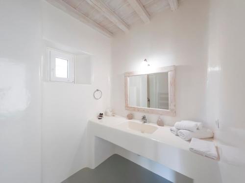 Un baño blanco con lavabo y espejo. en Villa Prive 77 Mykonos, en Mykonos ciudad