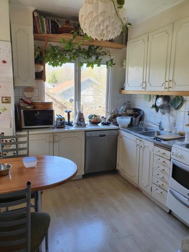 a kitchen with white cabinets and a wooden table at Unique homestay in Huddinge