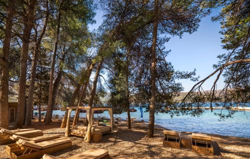 a group of picnic tables and chairs next to a lake at PLACES Hvar Villas by Valamar in Stari Grad