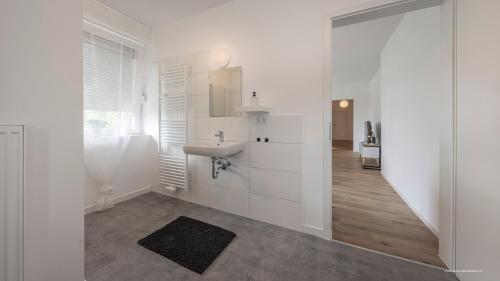 a white bathroom with a sink and a mirror at WineDesign Boxspring 8 Pers BASF Nähe Ludwigshafen und Mannheim in Frankenthal