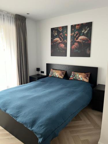 een slaapkamer met een groot blauw bed met 3 schilderijen aan de muur bij Boulevard 3F in Arnhem