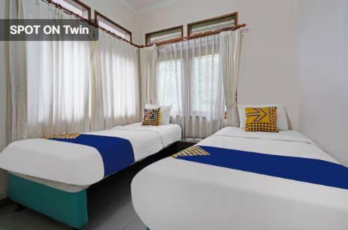 2 camas individuales en una habitación con cortinas en Mitra Dago Antapani Syariah en Bandung