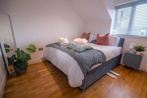 um quarto com uma cama com almofadas e uma planta em Cozy Living in Abbey Woods em Abbey Wood