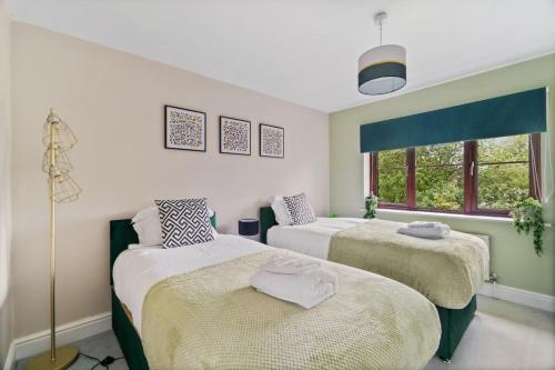 a bedroom with two beds and a window at The Pondmore-Spacious Detached house in Ashford with free parking close to M20 in Kent