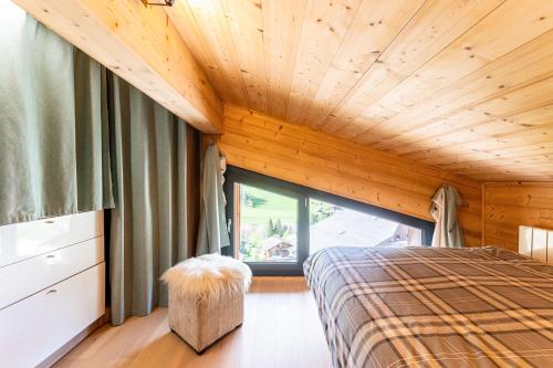 une chambre avec un lit et une grande fenêtre dans l'établissement Appartement Les Genevriers, au Grand-Bornand