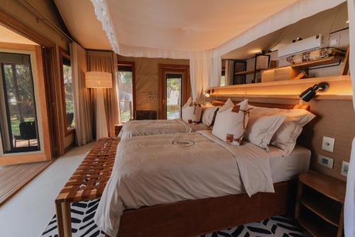Nuyanaya River Camp في Chiawa: غرفة نوم بسرير كبير في غرفة بها نوافذ