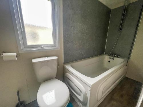 a bathroom with a toilet and a tub and a sink at Lovely Caravan With Side Decking And Free Wi-fi At Broadland Sands Ref 20016cf in Hopton on Sea